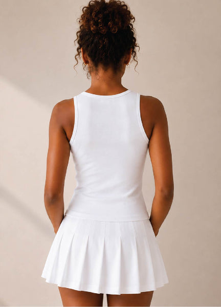 Woman wearing a white tennis tank with a tennis skirt